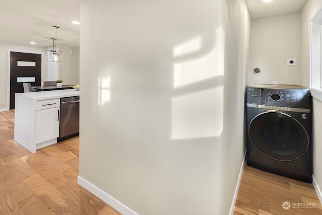 laundry area with light hardwood / wood-style floors, a chandelier, and washer / dryer