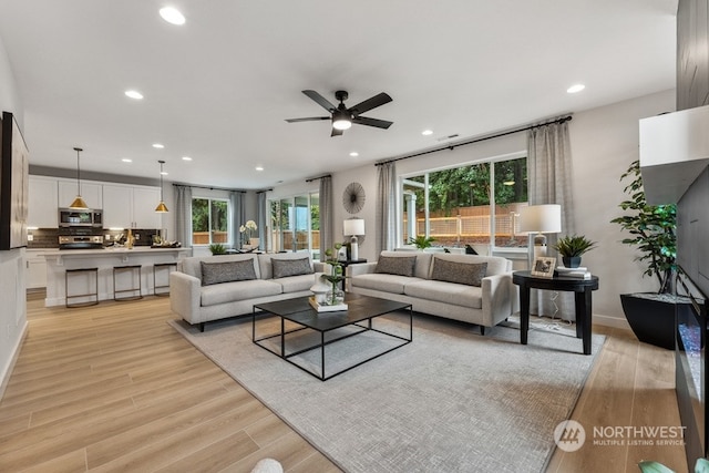 living room featuring recessed lighting, baseboards, light wood-type flooring, and a ceiling fan