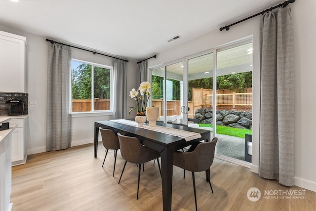 dining space featuring light wood finished floors, visible vents, and baseboards