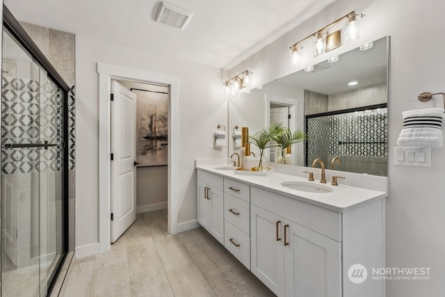 bathroom featuring a shower stall, double vanity, visible vents, and a sink