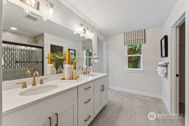 full bathroom with a sink, visible vents, tiled shower, and double vanity