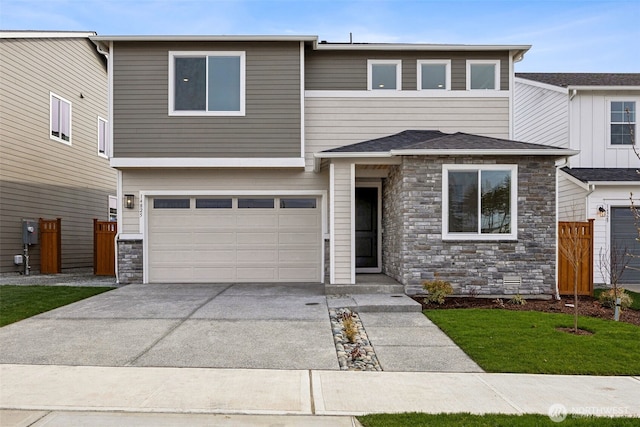 view of front of house with a garage, stone siding, concrete driveway, and fence