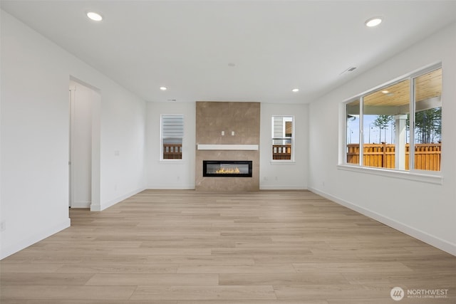 unfurnished living room with recessed lighting, baseboards, and light wood finished floors