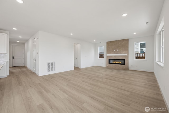 unfurnished living room with visible vents, recessed lighting, light wood-style floors, a fireplace, and baseboards