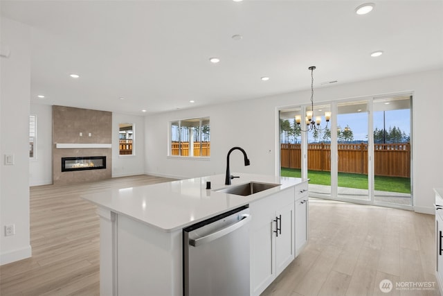 kitchen featuring a chandelier, a sink, light wood-style floors, and stainless steel dishwasher