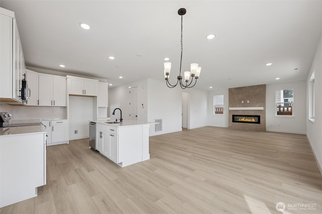 kitchen featuring light wood finished floors, visible vents, stove, a notable chandelier, and a sink