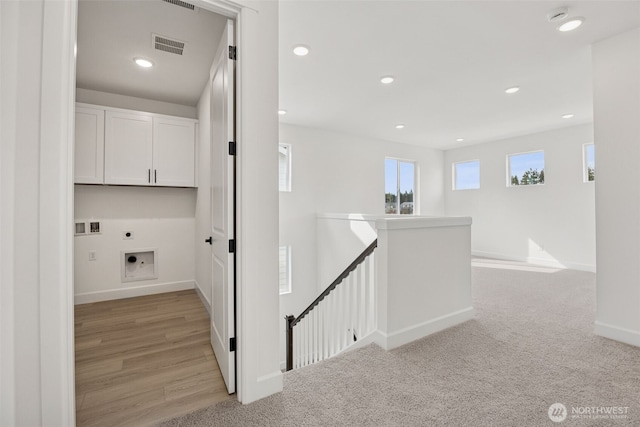 hallway with visible vents, baseboards, recessed lighting, light carpet, and an upstairs landing