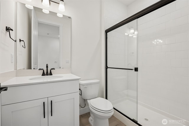 full bathroom featuring vanity, a shower stall, toilet, and wood finished floors