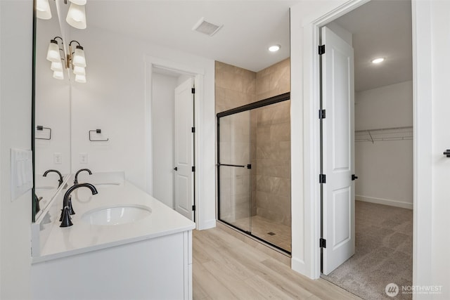 bathroom with a spacious closet, visible vents, a stall shower, and a sink