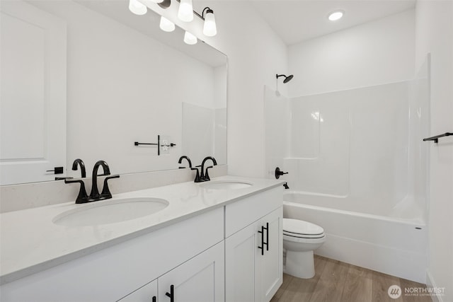 bathroom featuring a sink, shower / bath combination, toilet, and wood finished floors