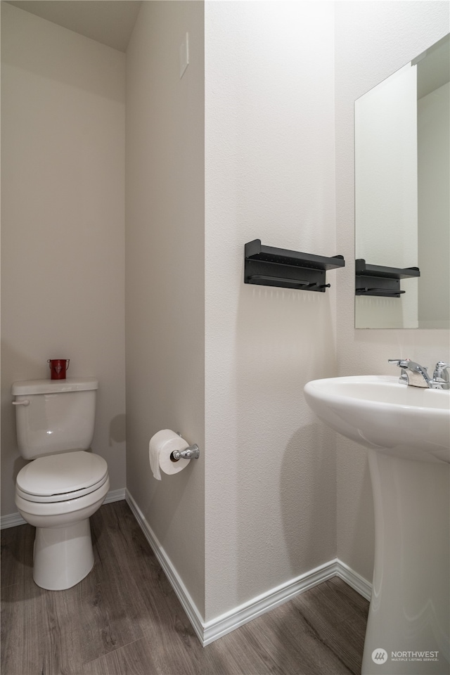 bathroom featuring wood-type flooring, toilet, and sink