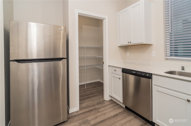 kitchen featuring white cabinets, appliances with stainless steel finishes, light hardwood / wood-style floors, and sink