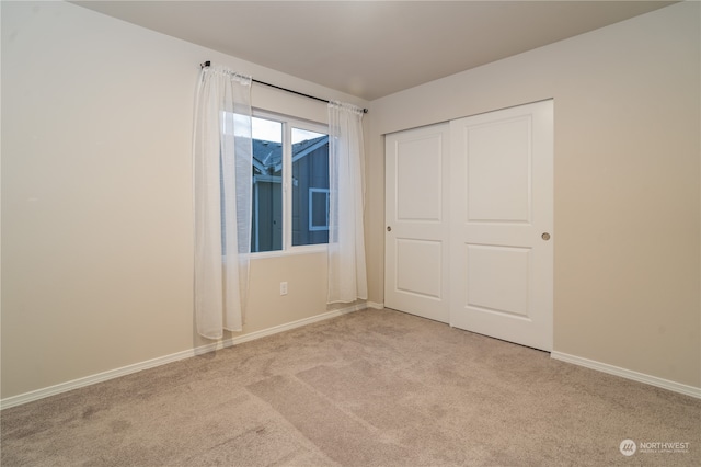 unfurnished bedroom featuring light colored carpet and a closet