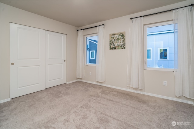 unfurnished bedroom with light colored carpet and a closet