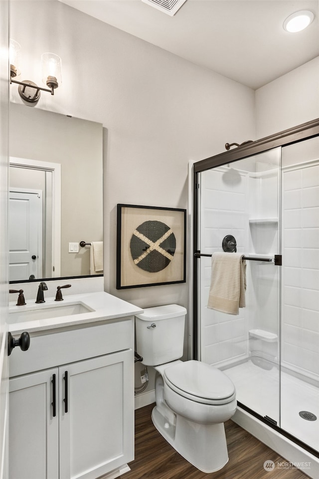 bathroom with a stall shower, vanity, toilet, and wood finished floors