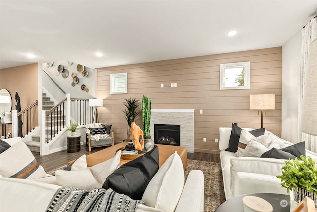 living room with wood walls, dark hardwood / wood-style floors, and a tile fireplace