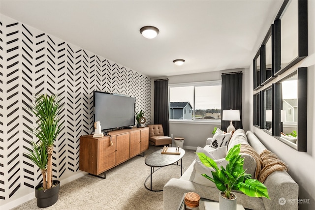 living room with carpet floors, wallpapered walls, an accent wall, and baseboards