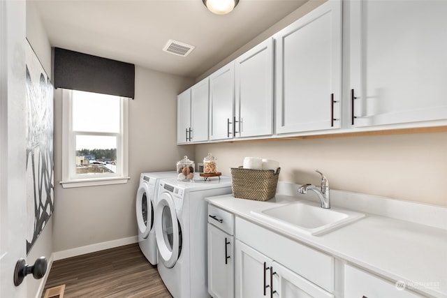 laundry room featuring dark wood-style floors, cabinet space, visible vents, a sink, and independent washer and dryer