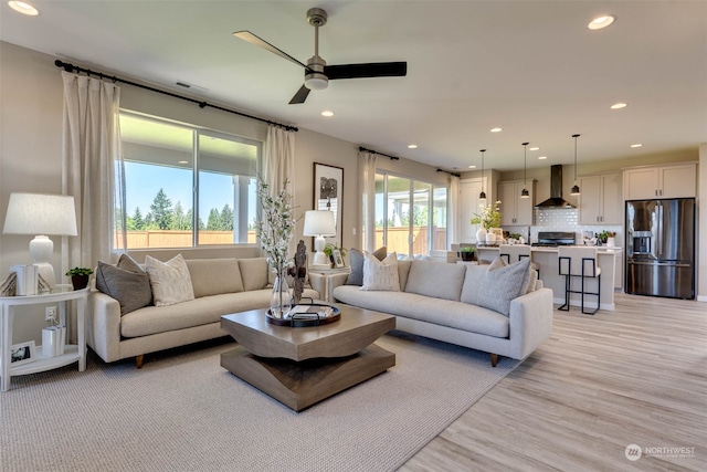 living room featuring light wood-type flooring, plenty of natural light, and ceiling fan