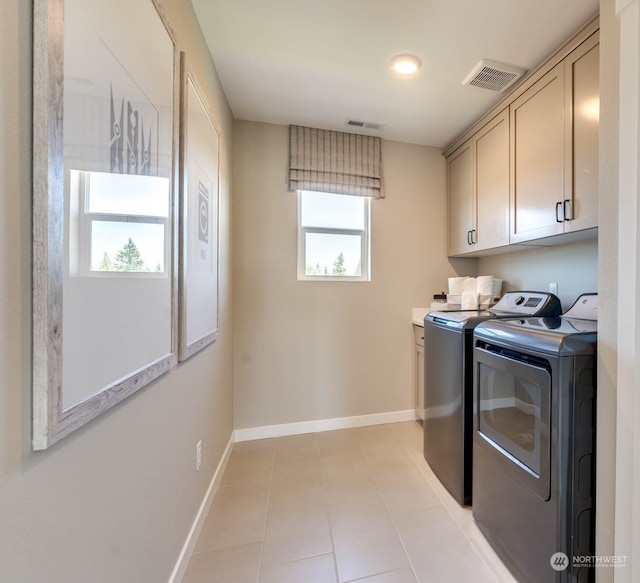 laundry room with light tile patterned floors, cabinets, and independent washer and dryer