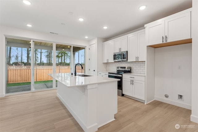 kitchen featuring sink, light hardwood / wood-style flooring, an island with sink, white cabinets, and appliances with stainless steel finishes