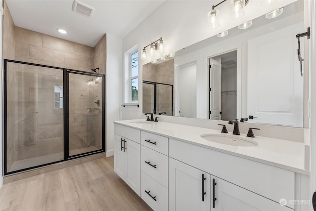 bathroom with hardwood / wood-style floors, vanity, and a shower with door