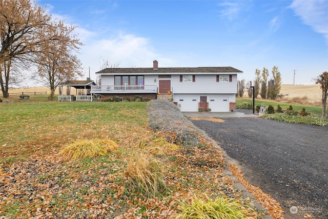 view of front of house featuring covered porch, a rural view, a garage, and a front lawn