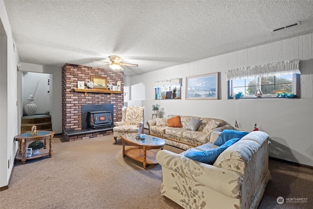 living room with a textured ceiling, carpet floors, a wood stove, and ceiling fan