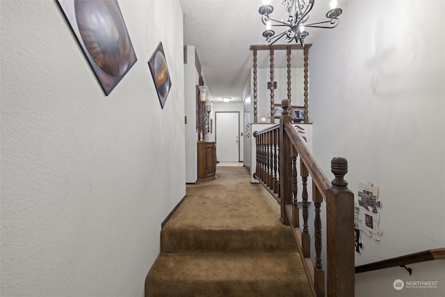 stairway with carpet flooring, a textured ceiling, and a notable chandelier