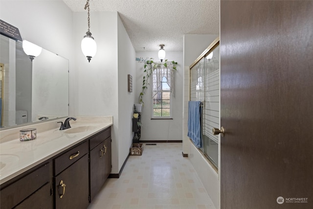 bathroom with combined bath / shower with glass door, a textured ceiling, and vanity