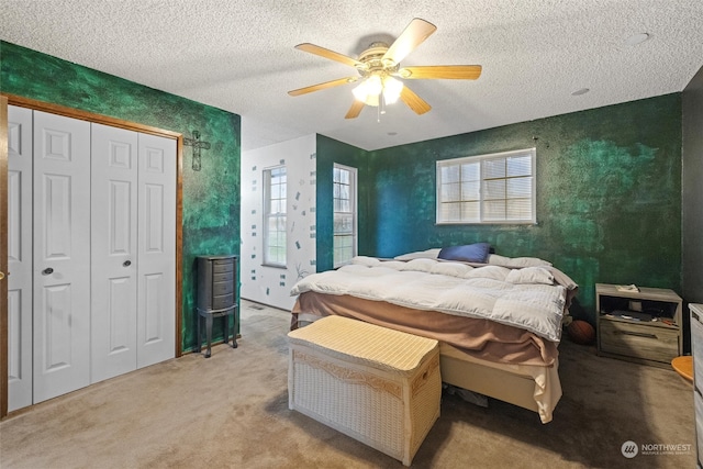 bedroom featuring light carpet, a textured ceiling, a closet, and ceiling fan