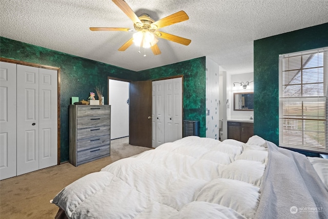 bedroom with light carpet, a textured ceiling, connected bathroom, and ceiling fan