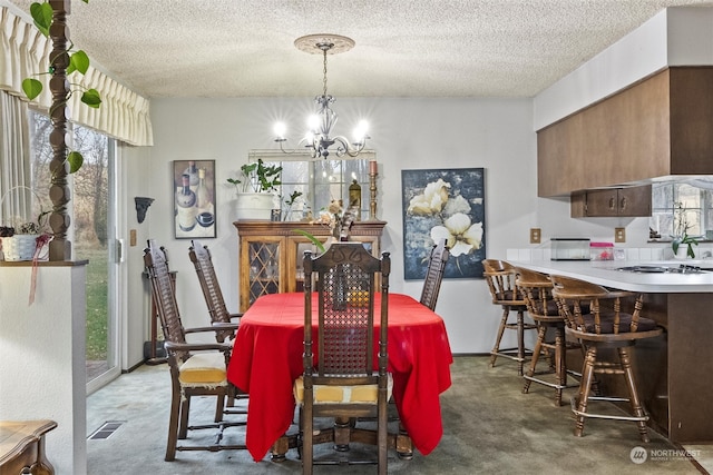 carpeted dining room featuring a wealth of natural light, a textured ceiling, and a notable chandelier