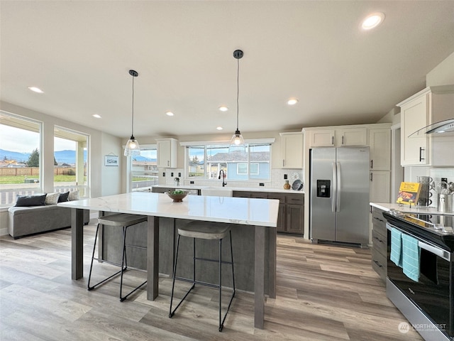 kitchen featuring plenty of natural light, a center island, white cabinetry, and stainless steel appliances