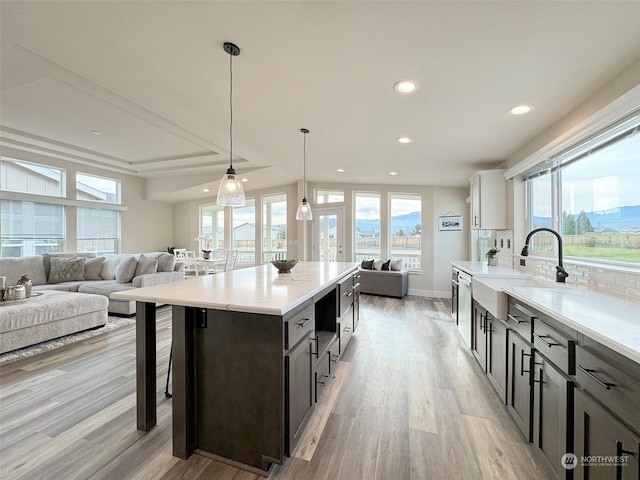 kitchen featuring decorative light fixtures, plenty of natural light, light hardwood / wood-style floors, and sink