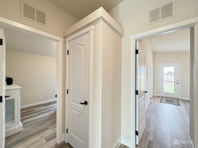 hallway with light wood-type flooring and vaulted ceiling