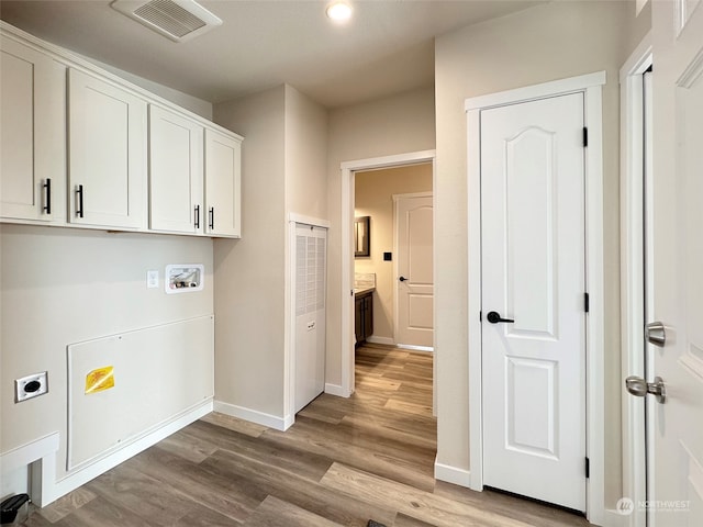 clothes washing area featuring hookup for an electric dryer, washer hookup, cabinets, and light hardwood / wood-style flooring