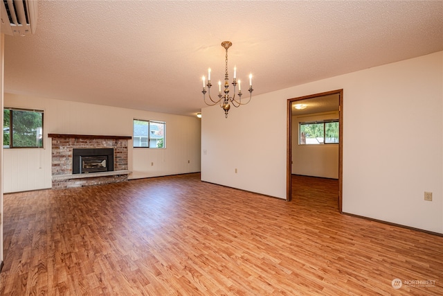 unfurnished living room with a wealth of natural light, a textured ceiling, and light hardwood / wood-style floors