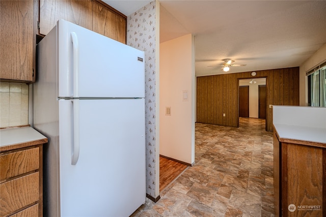 kitchen featuring tasteful backsplash, wooden walls, ceiling fan, and white fridge