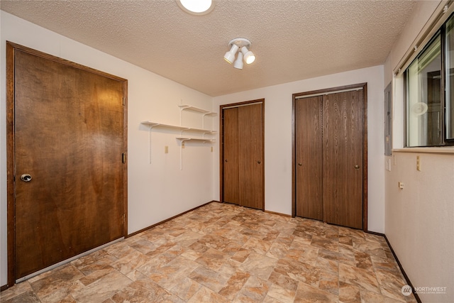 unfurnished bedroom featuring a textured ceiling and two closets