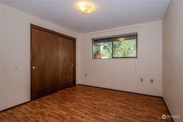 unfurnished bedroom with hardwood / wood-style floors, a textured ceiling, and a closet