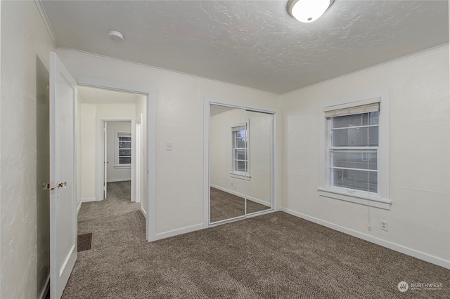 unfurnished bedroom with dark colored carpet, a textured ceiling, and a closet