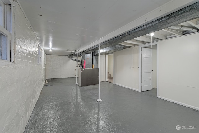 basement featuring heating unit and brick wall