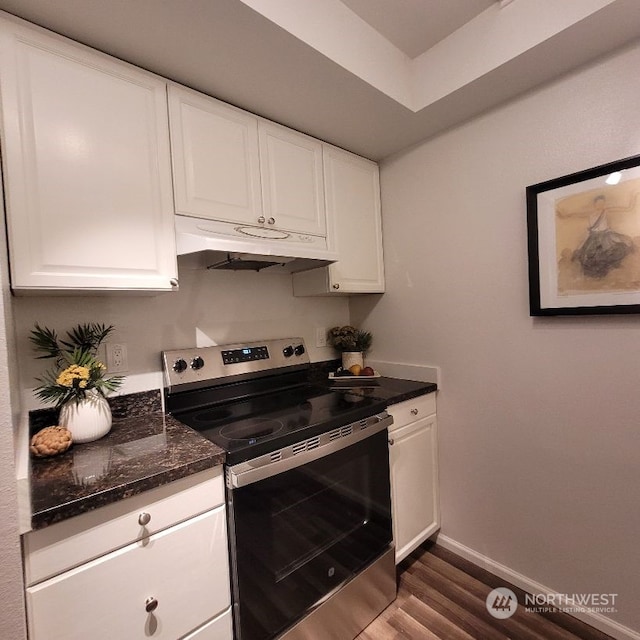 kitchen with dark stone counters, electric range, white cabinets, and dark wood-type flooring