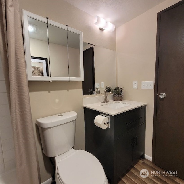 bathroom with hardwood / wood-style flooring, vanity, curtained shower, and toilet