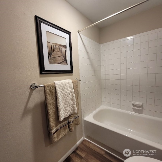 bathroom featuring hardwood / wood-style flooring, toilet, and tiled shower / bath