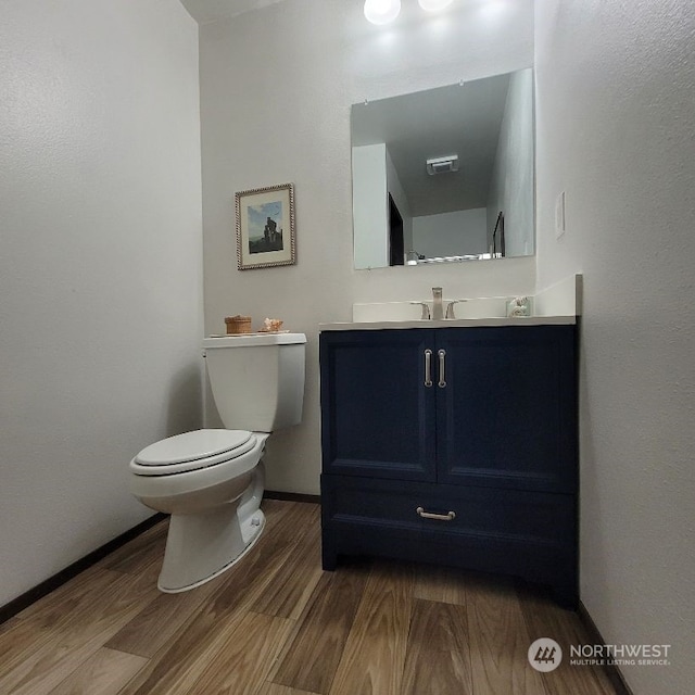 bathroom featuring toilet, vanity, and hardwood / wood-style flooring