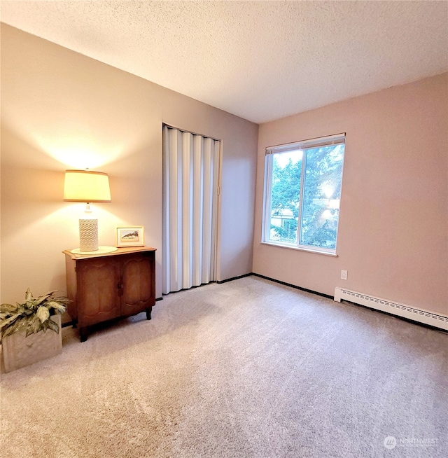 unfurnished bedroom with a textured ceiling, light carpet, and a baseboard heating unit