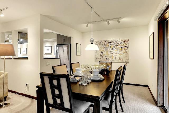 dining space featuring track lighting and light colored carpet