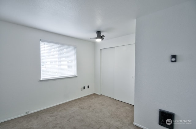 unfurnished bedroom featuring light carpet, a closet, and ceiling fan